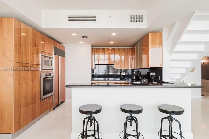 CUSTOM KITCHEN WITH HIGH END APPLIANCES BAR SEATING AREA THAT OVERLOOKS THE DINING ROOM FOR EASY SERVING.
