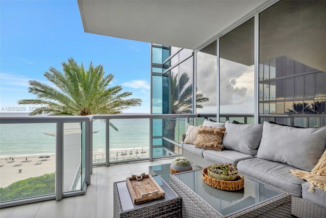 East-facing balcony with pool and beach views. Updated balcony furniture is not reflected in the photo.