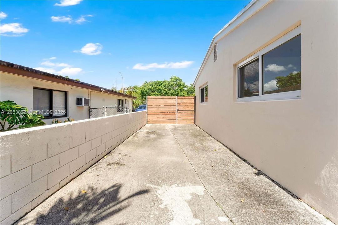Long gated side driveway with a modern wood privacy gate and block wall — offering secure parking for a boat and easy backyard access.