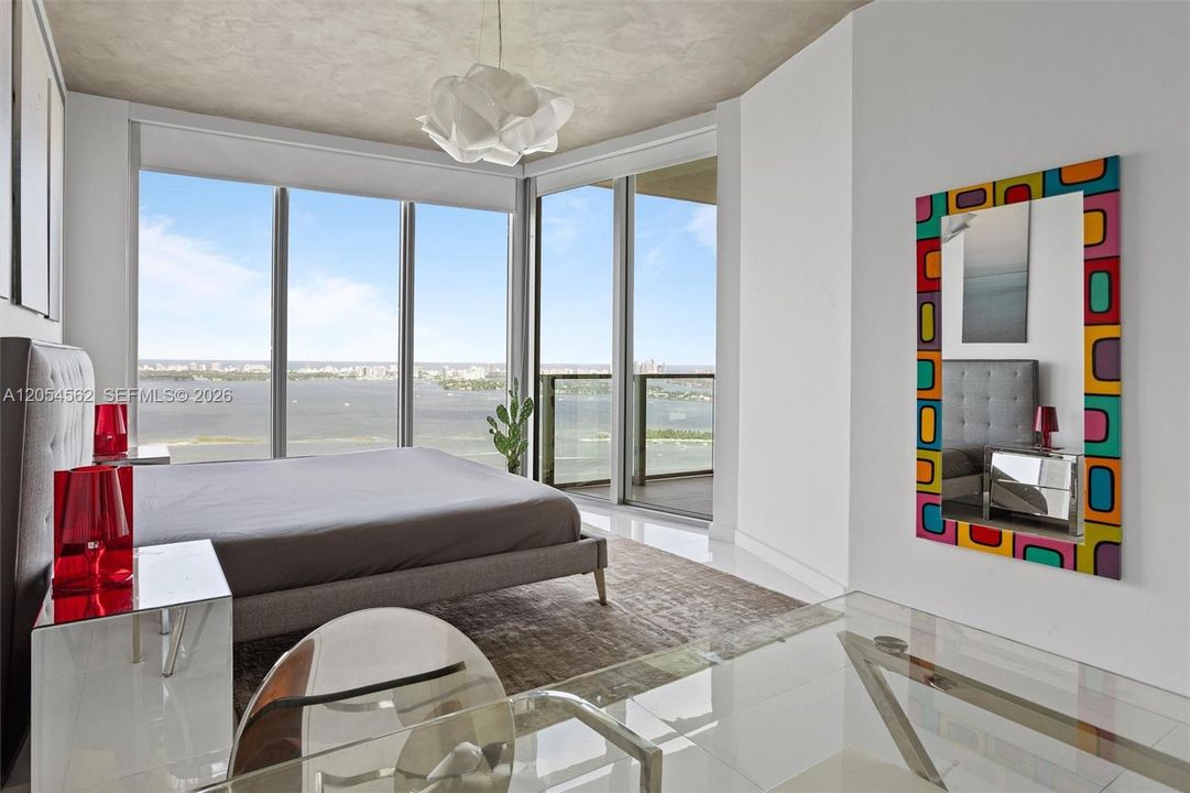 Bright furnished bedroom with floor-to-ceiling windows and Edgewater water views