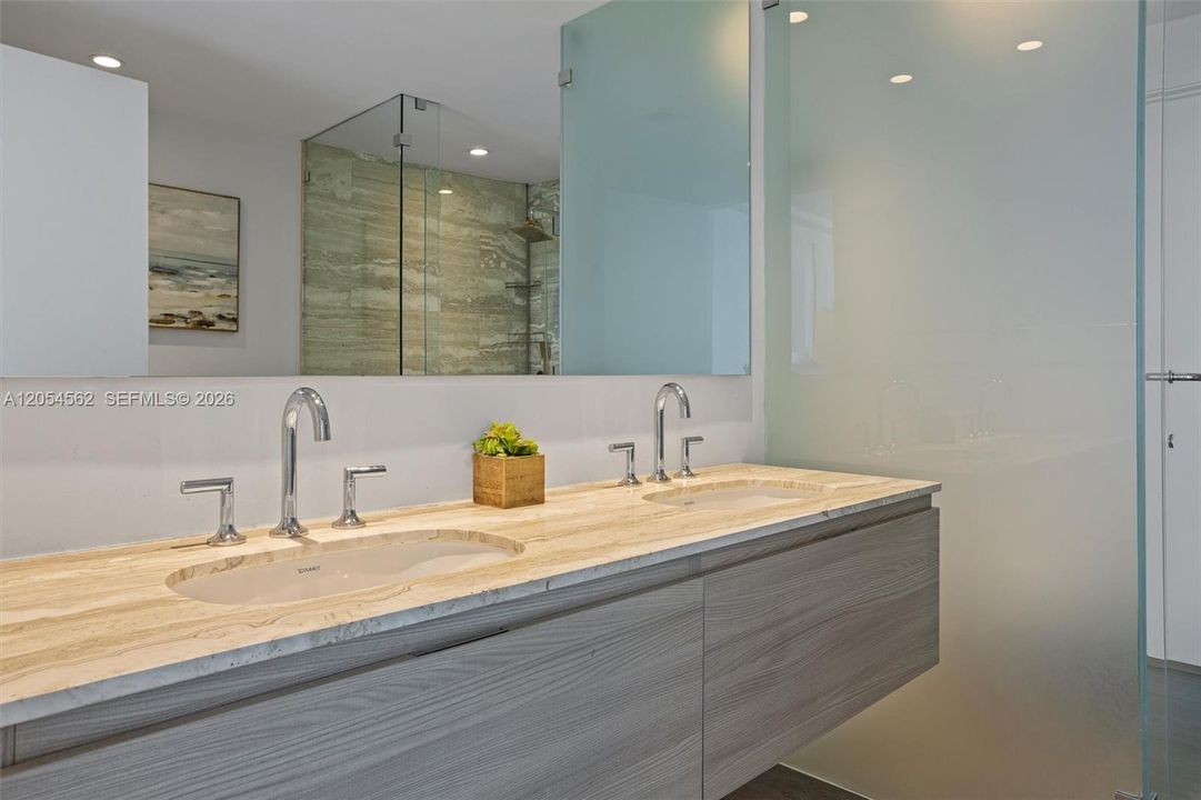 Spa-style primary bathroom with dual vanities and designer finishes