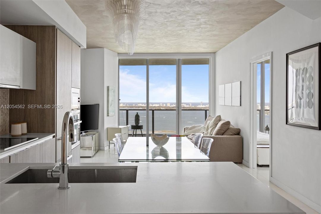 Open Miele kitchen flowing to the living area with floor-to-ceiling bay views