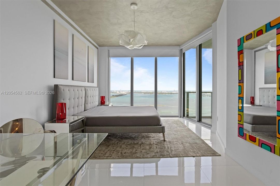 Furnished guest bedroom with natural light and serene water views