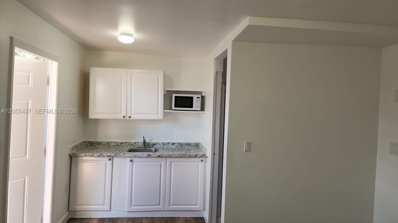 Cocina funcional y moderna: Un espacio optimizado y eficiente, diseñado con gabinetes blancos de estilo limpio que ofrecen un excelente almacenamiento. Equipada con electrodomésticos esenciales y una superficie de trabajo cómoda, esta cocina combina estilo y funcionalidad para aprovechar al máximo cada rincón