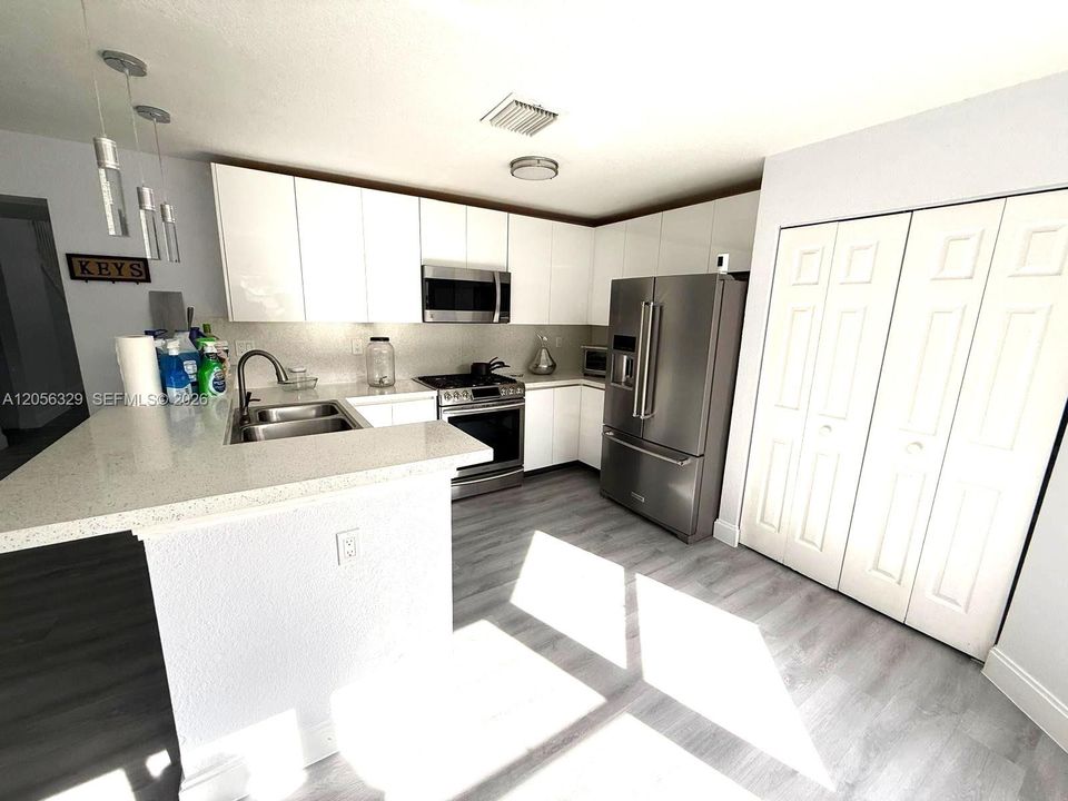 REMODELED WHITE ACRYLIC KITCHEN CABINETS AND GRANITE COUNTERTOPS