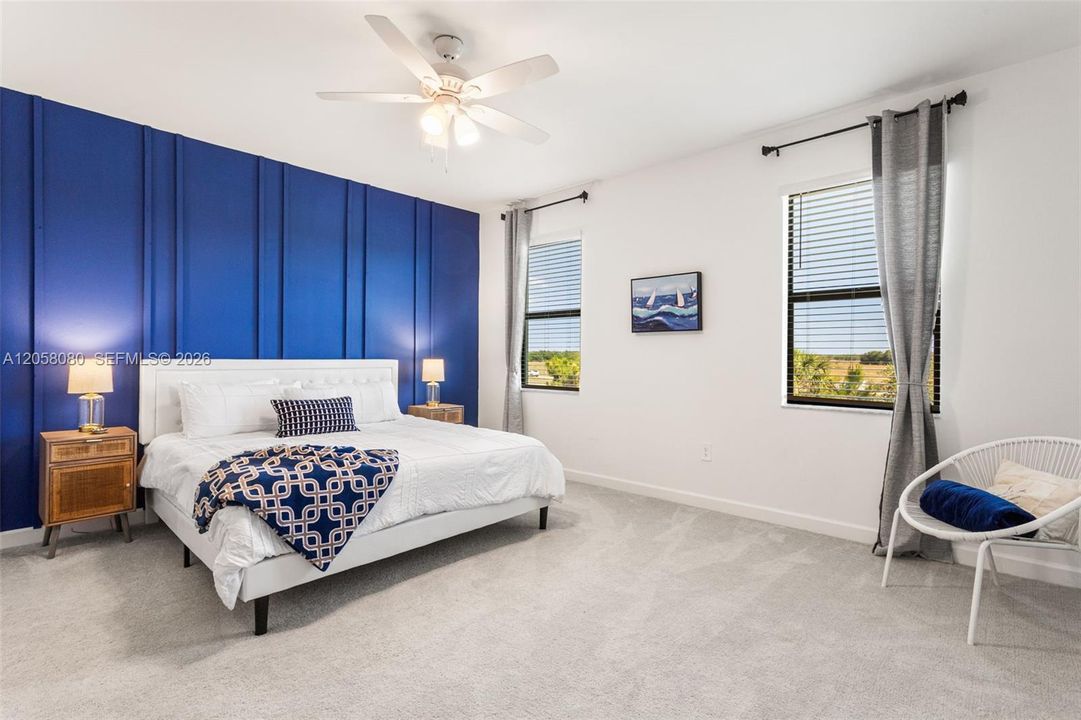 Upstairs, the carpeted second level features a large primary suite with a royal blue accent wall, dual closets, and a spacious sitting area