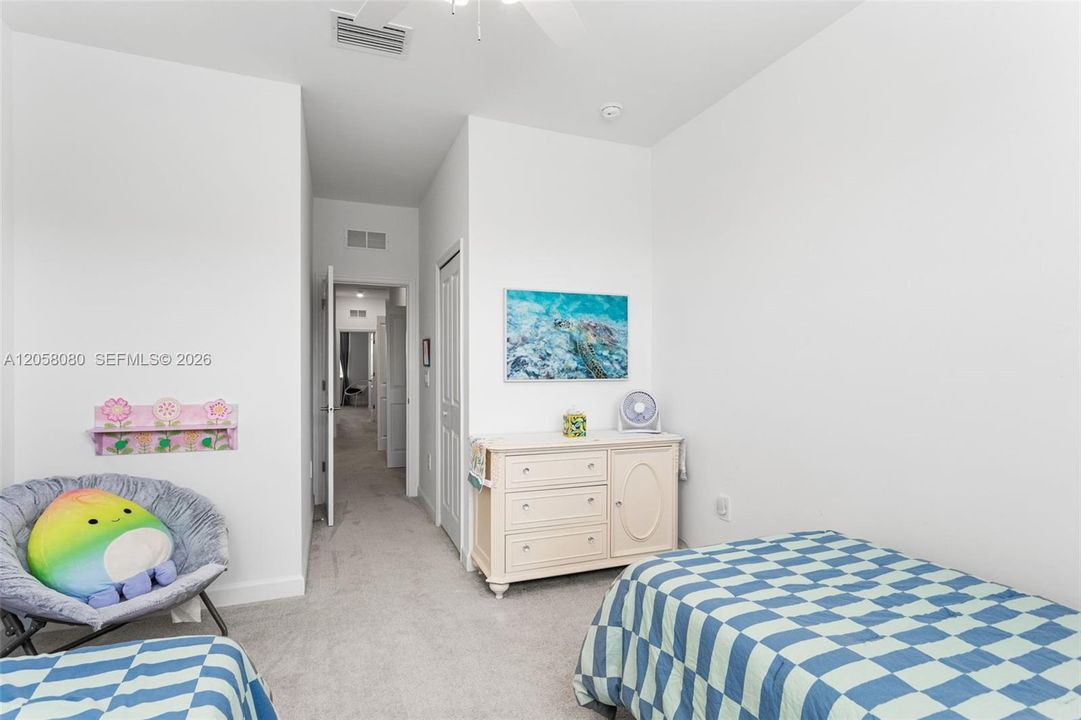 Spacious secondary bedroom with high ceilings, soft carpeting, ceiling fan, and generous closet space