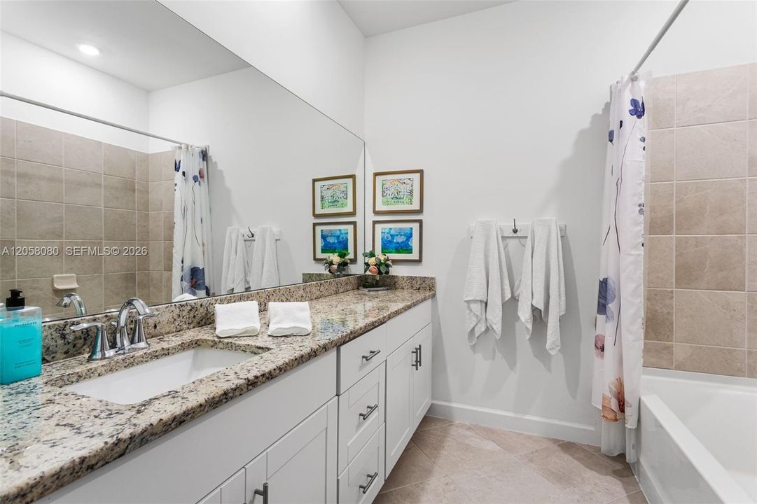A full hallway bathroom includes a large vanity with granite countertop, tub/shower combo, and linen storage