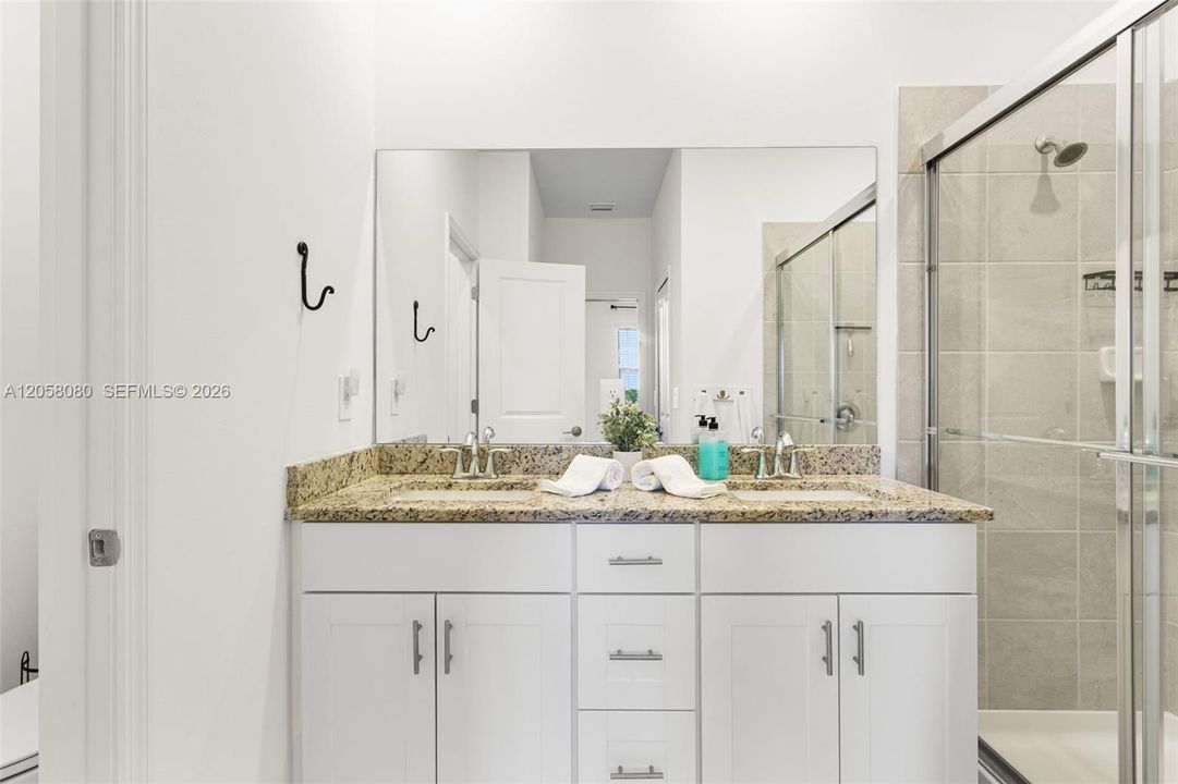 The ensuite bath offers granite countertops, dual sinks, and a glass-enclosed walk-in shower