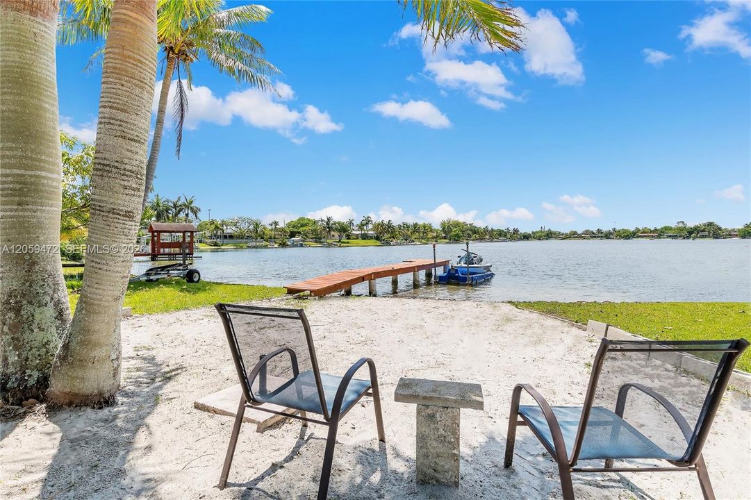 Stunning waterfront views framed by swaying palms, with a private patio set up for outdoor dining and relaxation right on the water's edge.