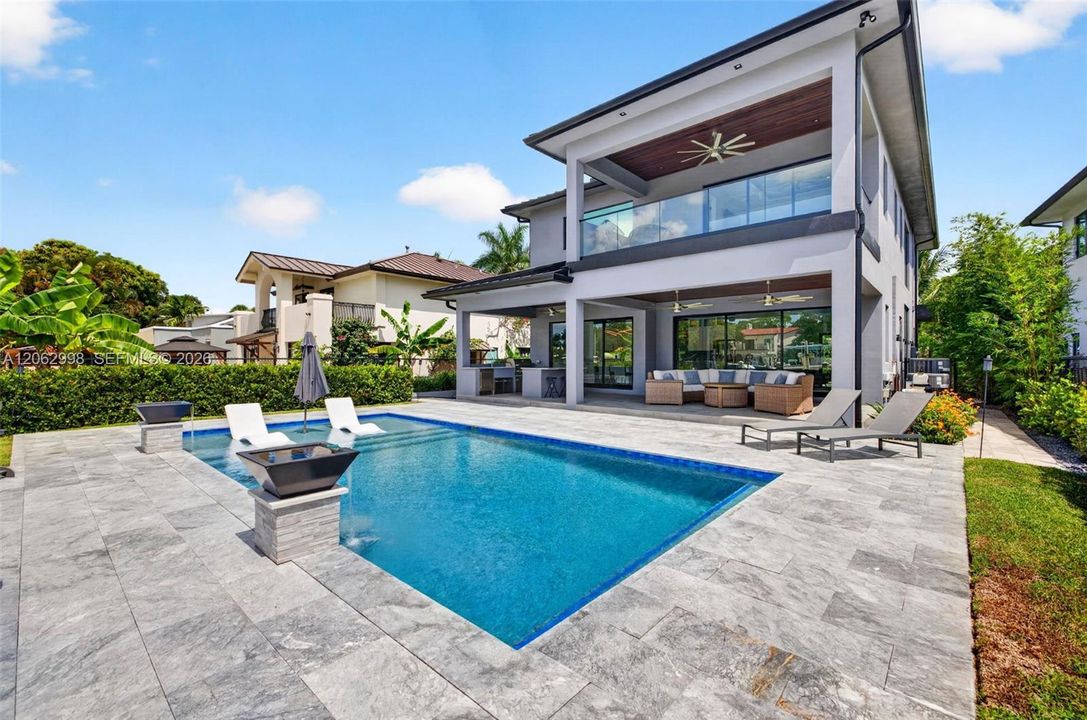 Salt chlorinated pool w/ water features, LED color changing light, sun shelf with umbrella hole and in water stools. Stone decking surrounds the pool