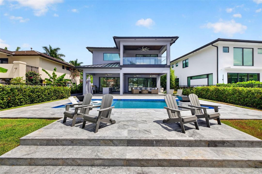 Salt chlorinated pool w/ water features, LED color changing light, sun shelf with umbrella hole and in water stools. Stone decking surrounds the pool