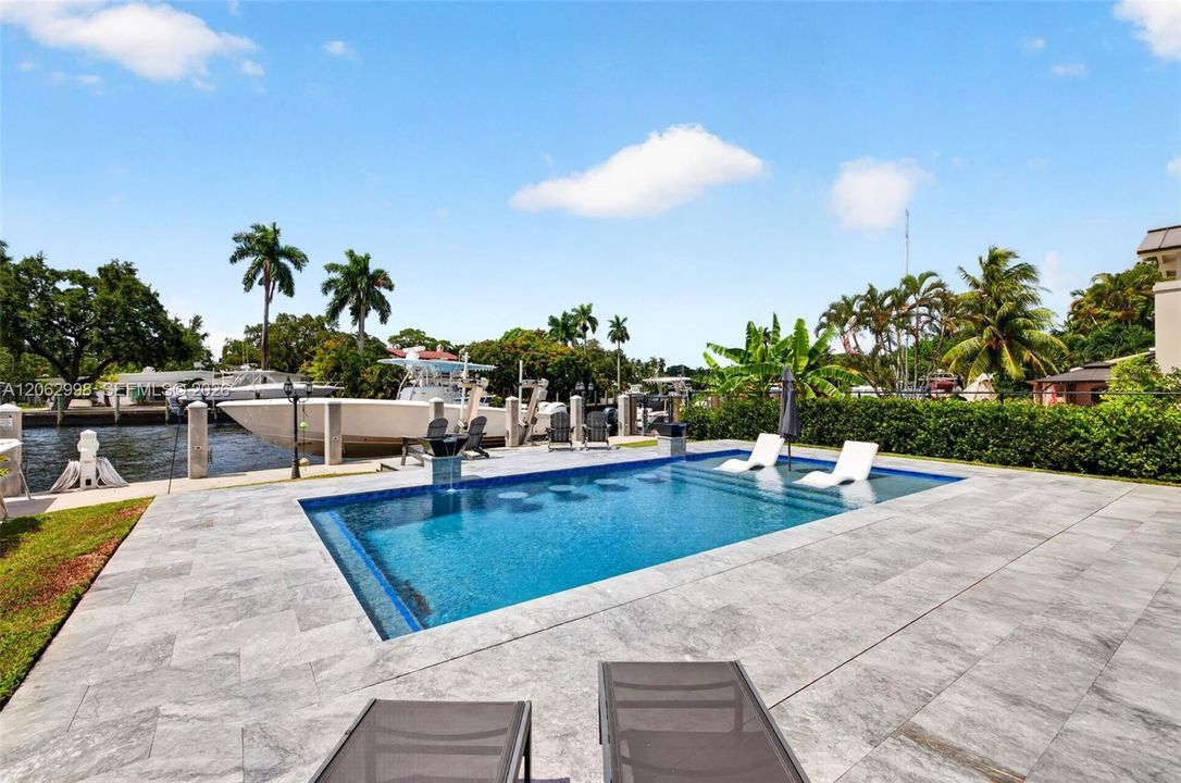 Covered patio w/ T&G ceilings, fans, fire pit seating and outdoor kitchen overlooks the gorgeous wide New River views and pool area
