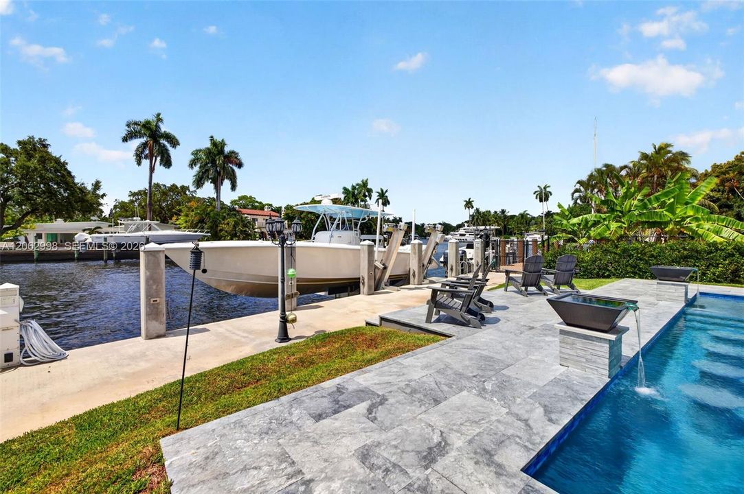 Salt chlorinated pool w/ water features, LED color changing light, sun shelf with umbrella hole and in water stools. Stone decking surrounds the pool