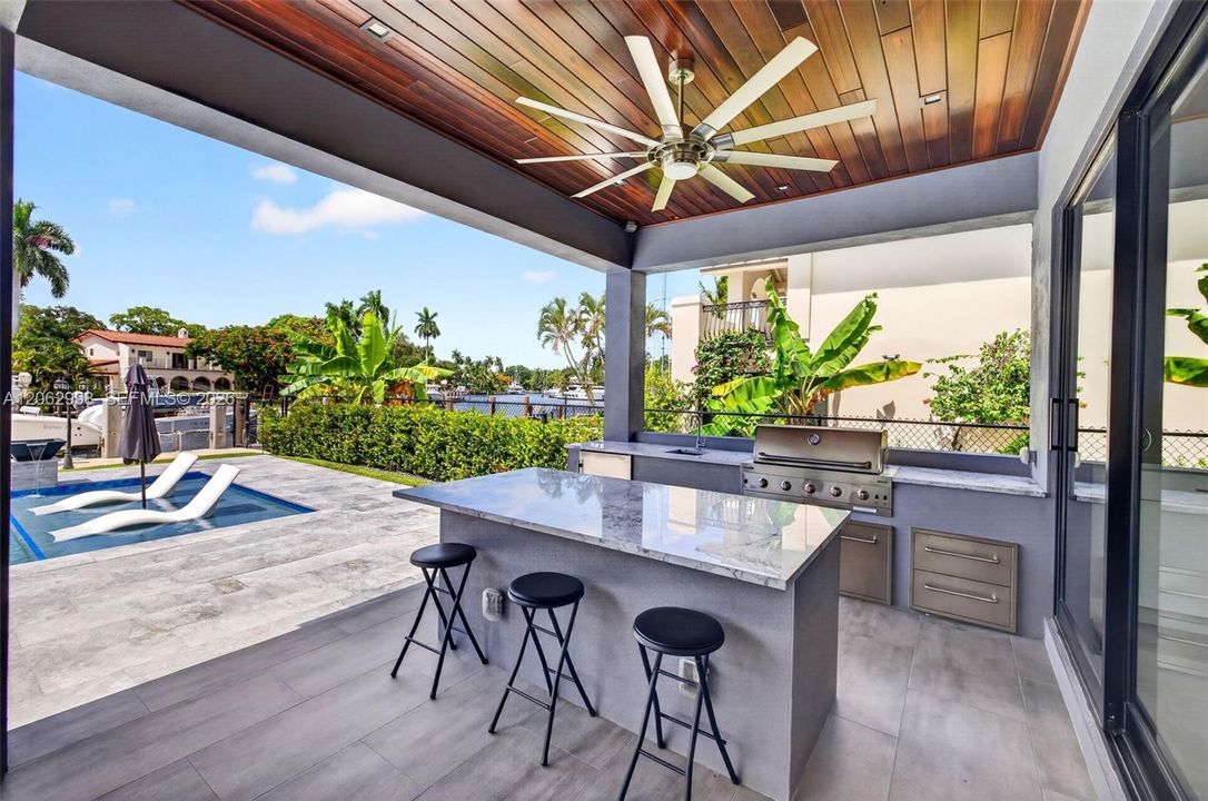 Covered patio w/ T&G ceilings, fans, fire pit seating and outdoor kitchen overlooks the gorgeous wide New River views and pool area