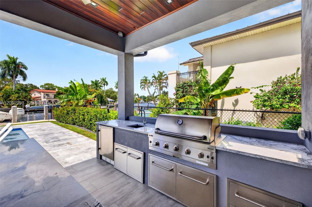 Covered patio w/ T&G ceilings, fans, fire pit seating and outdoor kitchen overlooks the gorgeous wide New River views and pool area