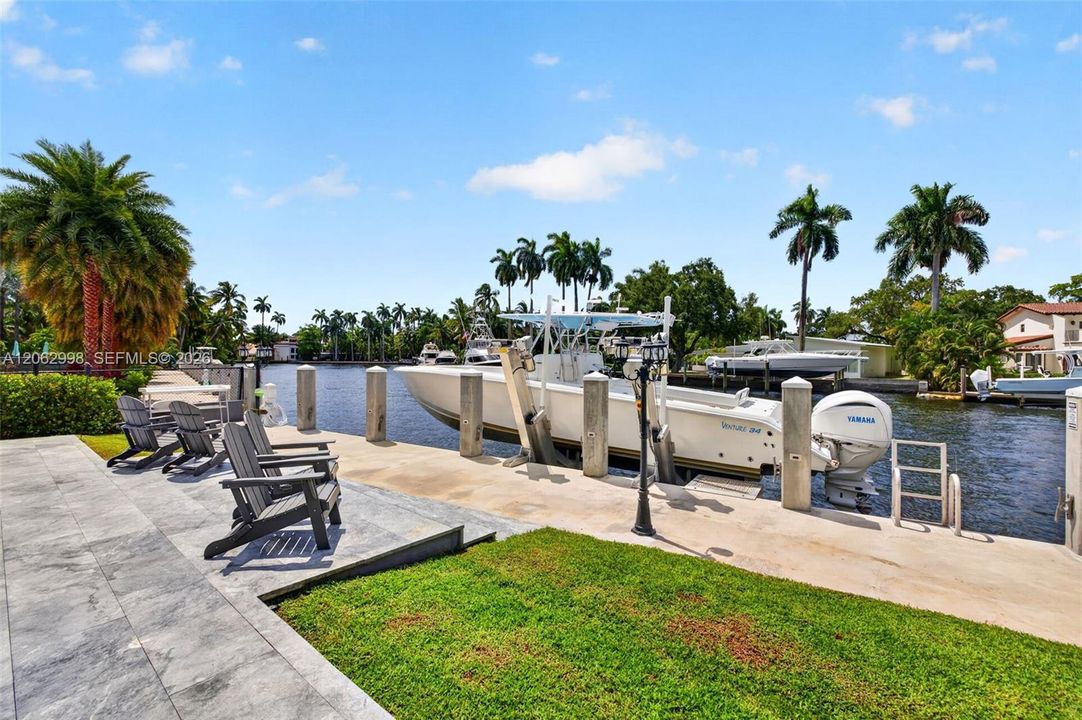 View from the new concrete dock and seawall to the Salt chlorinated pool w/ water features, LED color changing light, sun shelf with umbrella hole and in water stools. Stone decking surrounds the pool