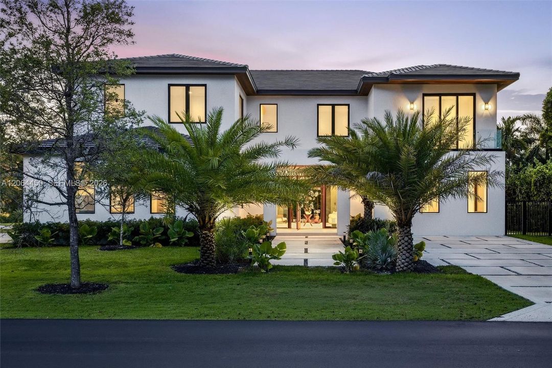 Two-story contemporary exterior featuring a smooth stucco finish, dark-framed multi-pane windows, a tiled roof, and a paved geometric driveway