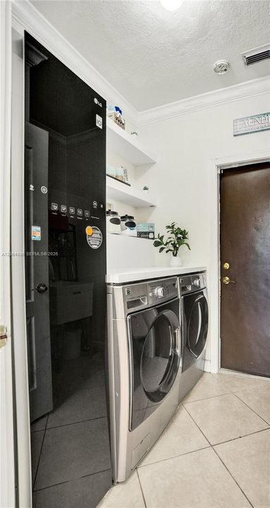 LAUNDRY AREA FEATURES WASHER, DRYER AND STEAM CLOTHING CARE SYSTEM TO STEAM, DEODORIZE AND SANITIZE CLOTHES, BLANKETS, TOYS. DOOR LEADING TO STORAGE/UTILITY AREA.