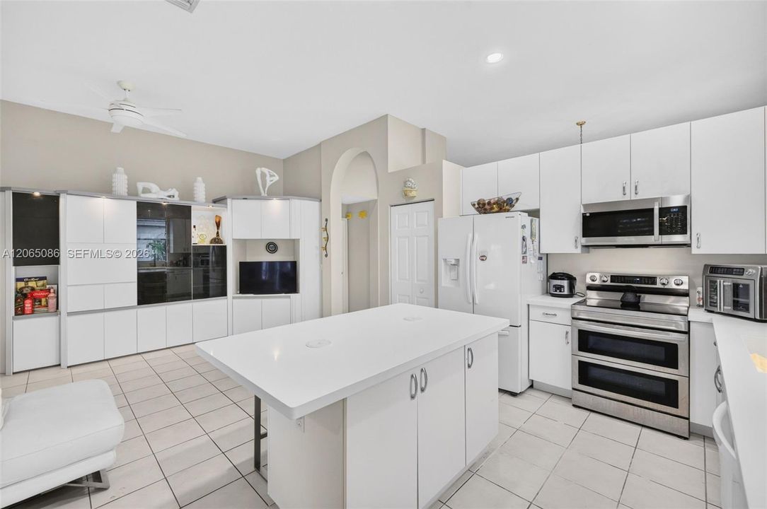 Spacious open concept kitchen w/ built in wall unit, volume ceilings and solid surface counters