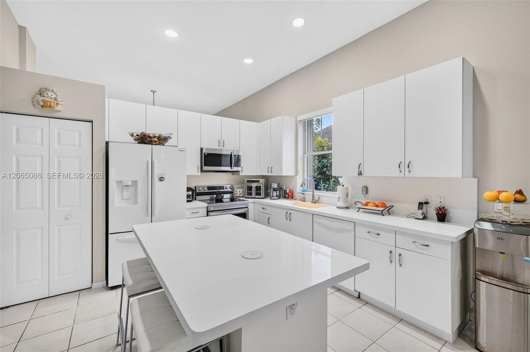 Spacious open concept kitchen w/ built in wall unit, volume ceilings and solid surface counters