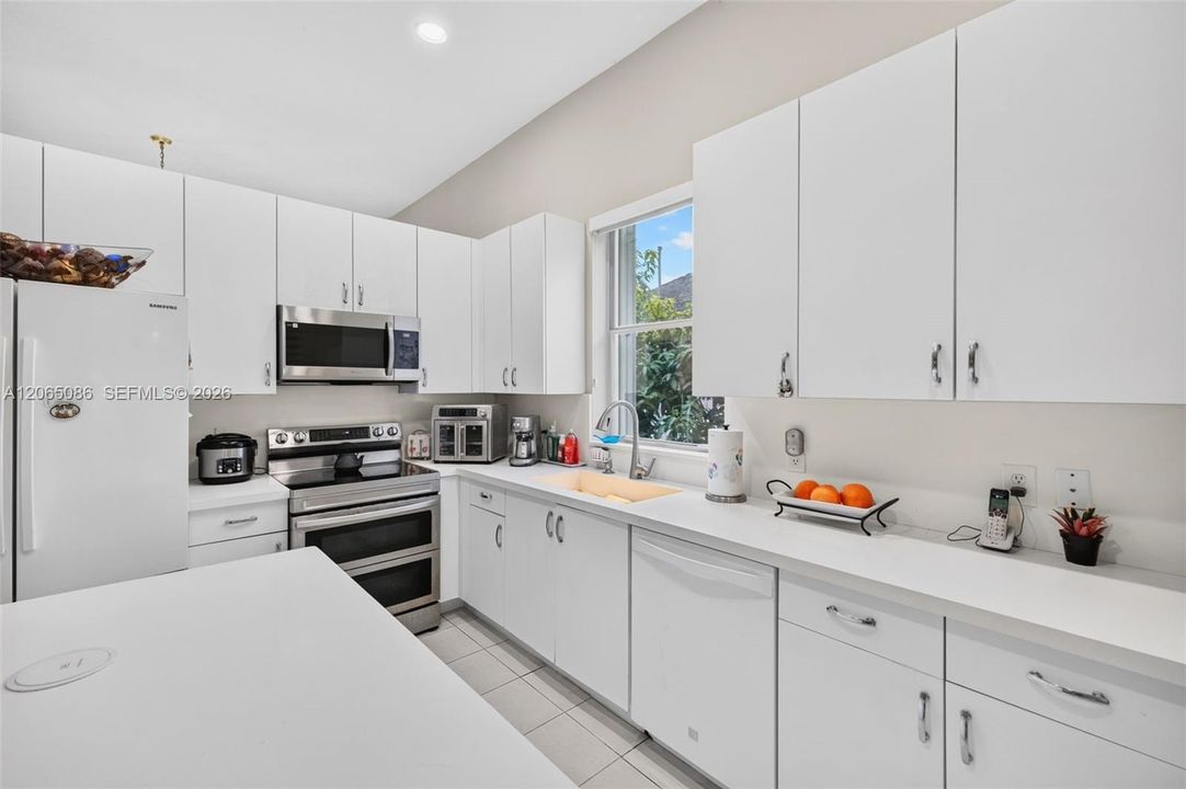 Spacious open concept kitchen w/ built in wall unit, volume ceilings and solid surface counters