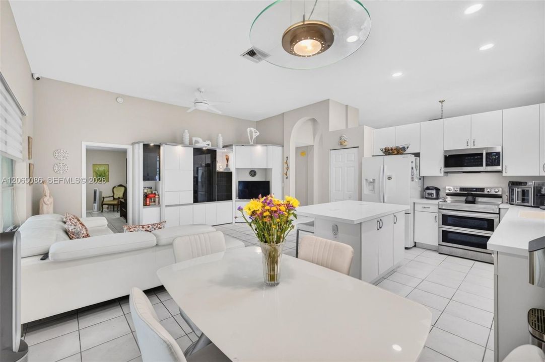 Spacious open concept kitchen w/ built in wall unit, volume ceilings and solid surface counters