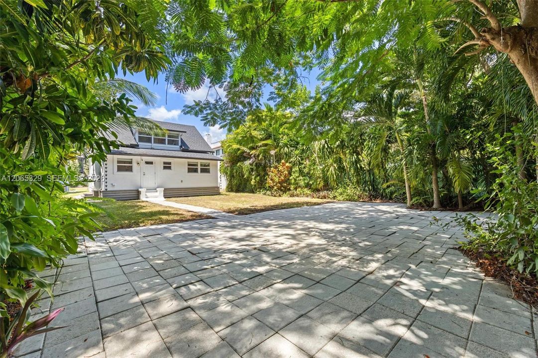A deep backyard surrounded by the kind of mature tropical greenery South Miami is known for.