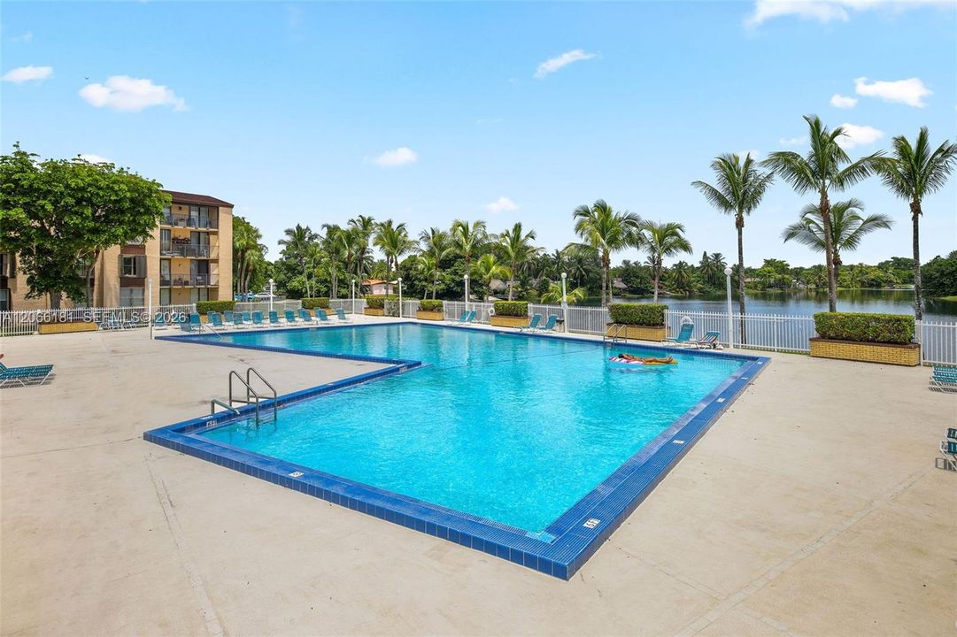 Primary swimming pool overlooking lake next to tennis courts
