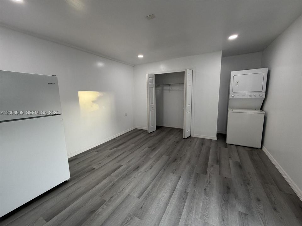 Studio living area with closet, refrigerator, and in-unit laundry