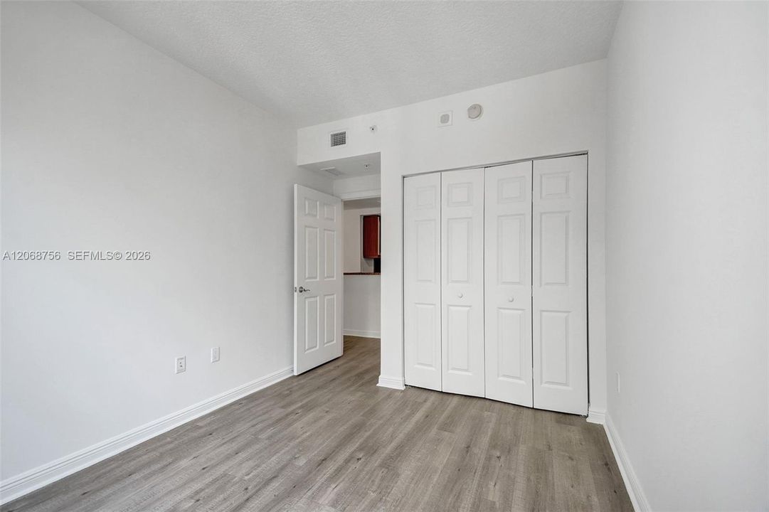 second bedroom, Interior room featuring wood-finish flooring, four-panel folding closet doors, and a solid-core swing door