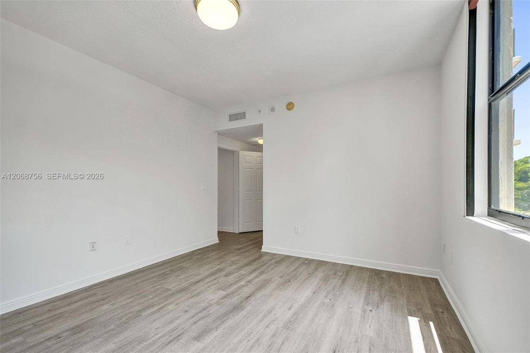 master bedroom, flooring, a large window with black framing, and a flush-mount circular ceiling fixture