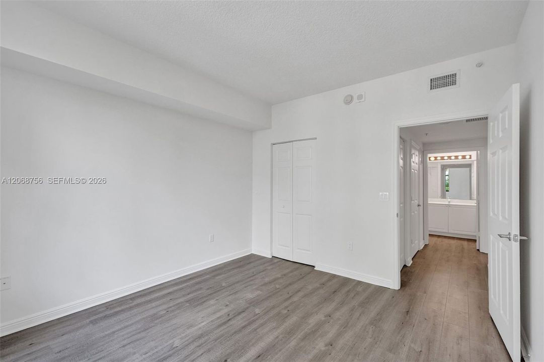 third bedroom, Neutral-toned wood-finish flooring, white walls, and a black-framed window