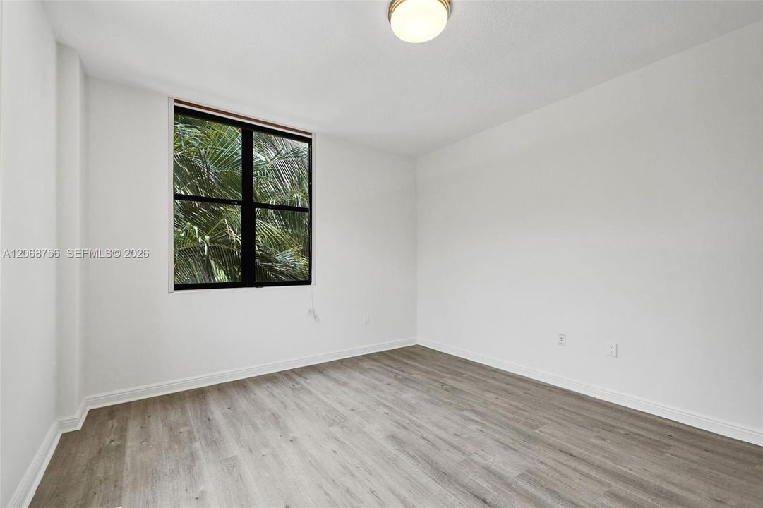 second bedroom, Room featuring wood-finish flooring, a neutral color palette, and a large window with a black frame
