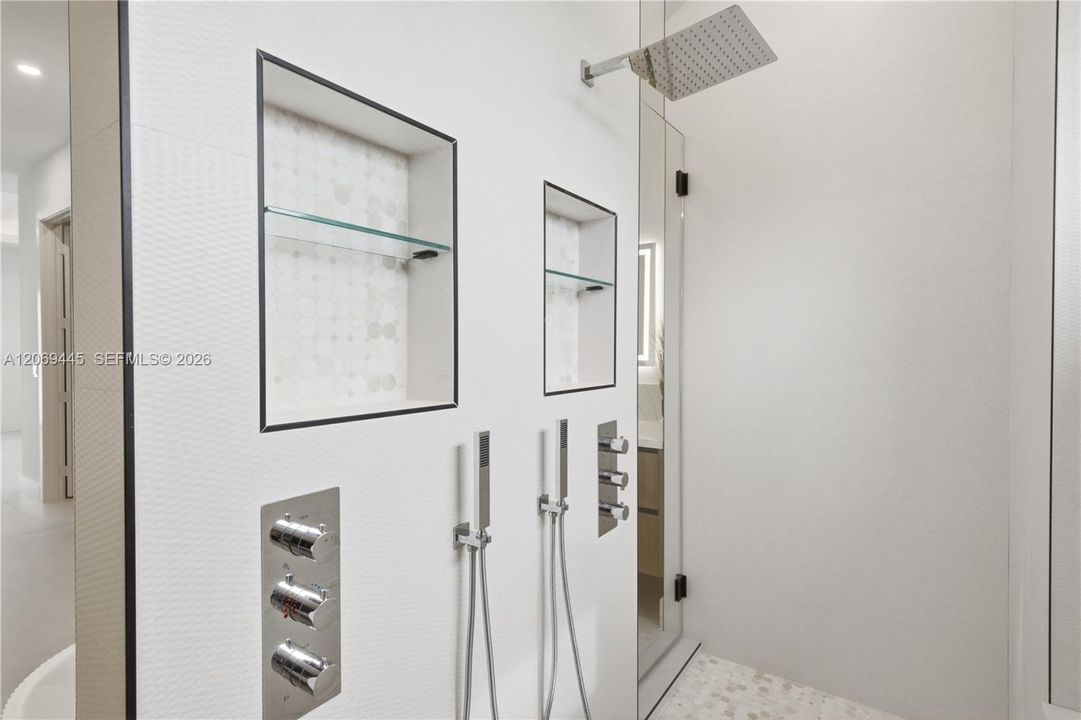 Oversized glass-enclosed shower offers a rainfall showerhead, dual handheld fixtures and multiple body jets.