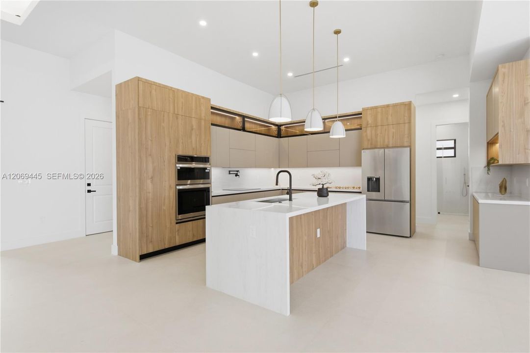 Chef-inspired gourmet kitchen showcasing sleek European-style custom cabinetry, Taj-Mahal inspired quartz countertops w/ waterfall island
