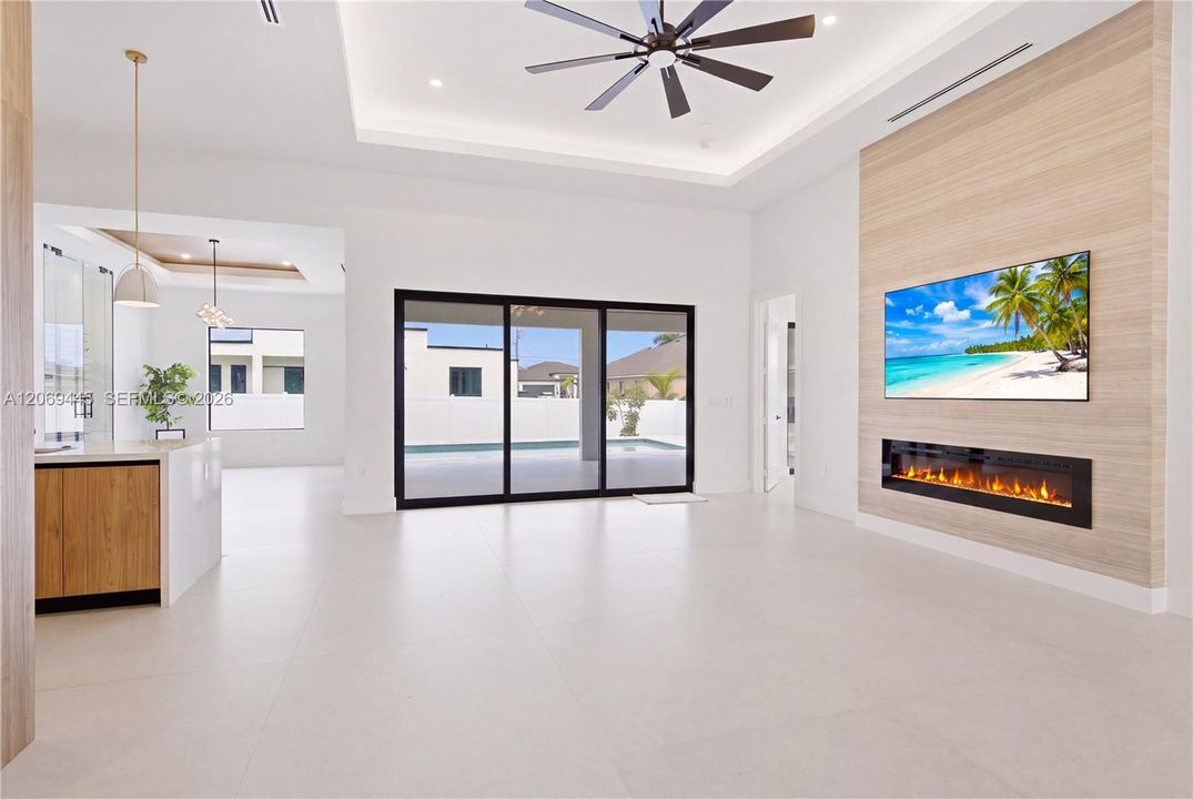 Spectacular great room features linear electric fireplace w/ floor-to-ceiling feature wall, creating the perfect gathering space while oversized sliding doors seamlessly blend indoor & outdoor living.