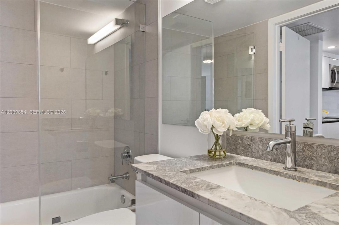 This beautifully designed second bathroom seamlessly blends style and convenience. Thoughtfully positioned with dual access from both the second bedroom and the entrance hallway, it offers the perfect balance of privacy and accessibility for residents and guests alike. The modern design features a sleek vanity with a polished stone countertop, a large mirror that enhances brightness, and contemporary fixtures that elevate the space. The bathtub and shower combination