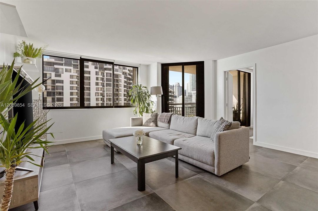 This stunning open-concept space is designed for both functionality and style. The extra-large island features additional storage beneath, offering plenty of room for kitchen essentials and organization. A conveniently located closet next to the island provides even more storage options, ensuring a clutter-free living experience. Sleek large slate tile flooring spans the entire space, adding a contemporary touch while being both durable and easy to maintain. Recessed lighting and modern track fixtures