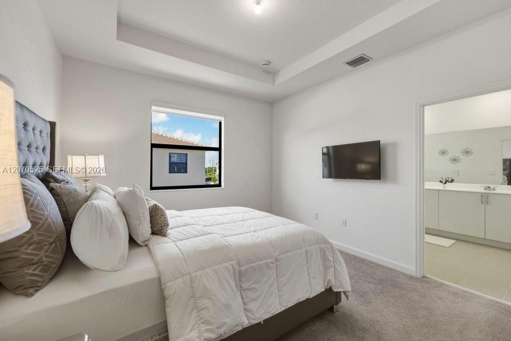 The primary bedroom is spacious and bright, with room for a substantial bed, nightstands, television and additional furniture without feeling crowded.