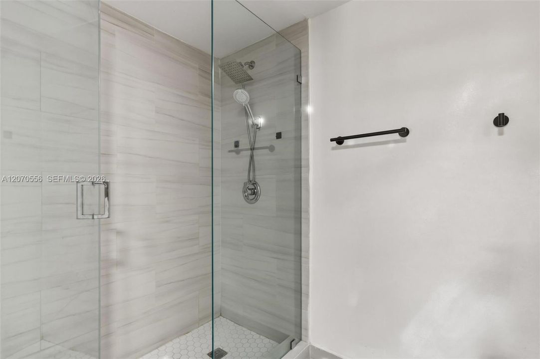 A spacious walk-in shower with a sleek glass enclosure, modern finishes, and an oversized rain-style showerhead.