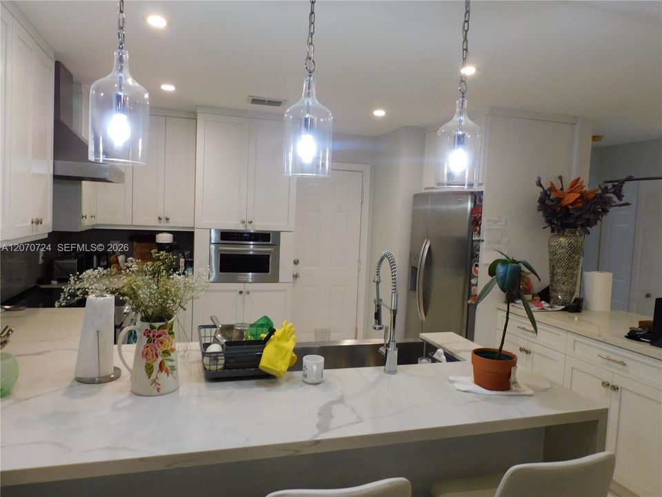 Upgraded and redesigned Kitchen - Quartz countertops - Tiled backsplash - Kitchen Aid Appliances - Farm house oversized undermount sink - Overhead ventilation hood - Snack counter.