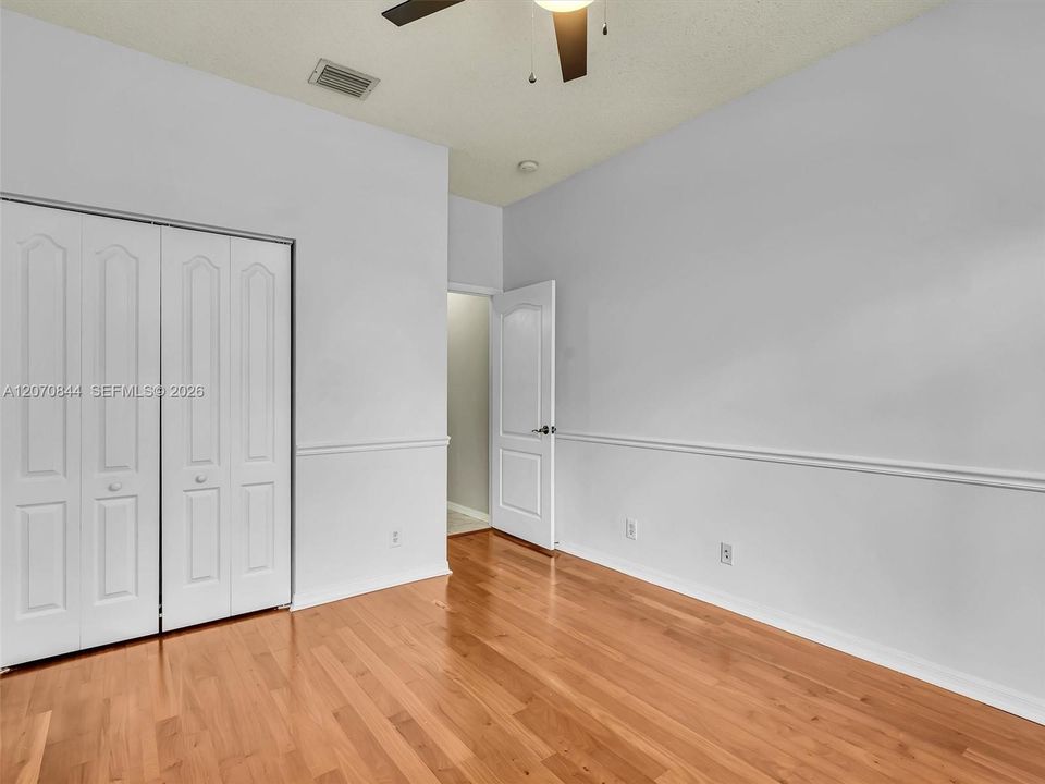Spacious second bedroom featuring hardwood floors, a charming bay window, and abundant natural light, creating a warm and inviting space.