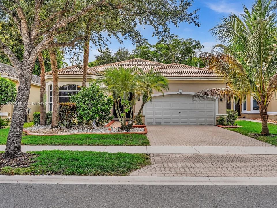 Inviting curb appeal with a beautifully maintained front landscape and a spacious driveway offering additional parking.