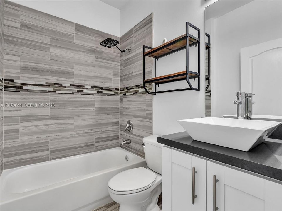 Second fulll bathroom featuring a tub/shower combination, elegant quartz countertops, ample storage space, and convenient linen closet for added functionality