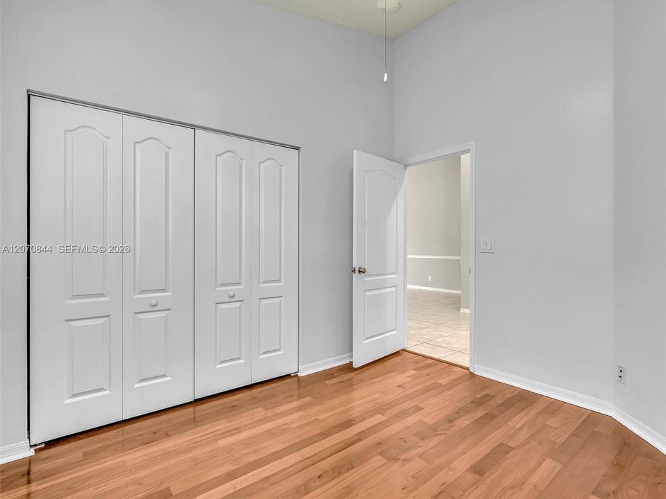Comfortable third bedroom featuring hardwood floors and abundant natural light, offering a cozy yet functional space.
