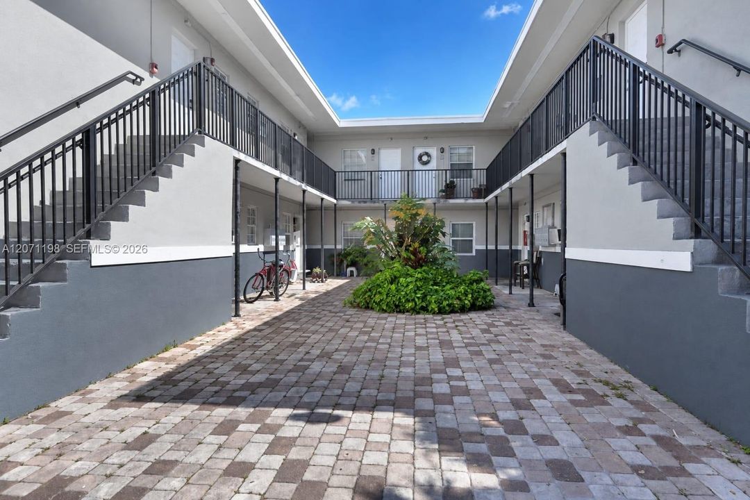 Courtyard featuring paver hardscaping, dual exterior staircases, and metal railings