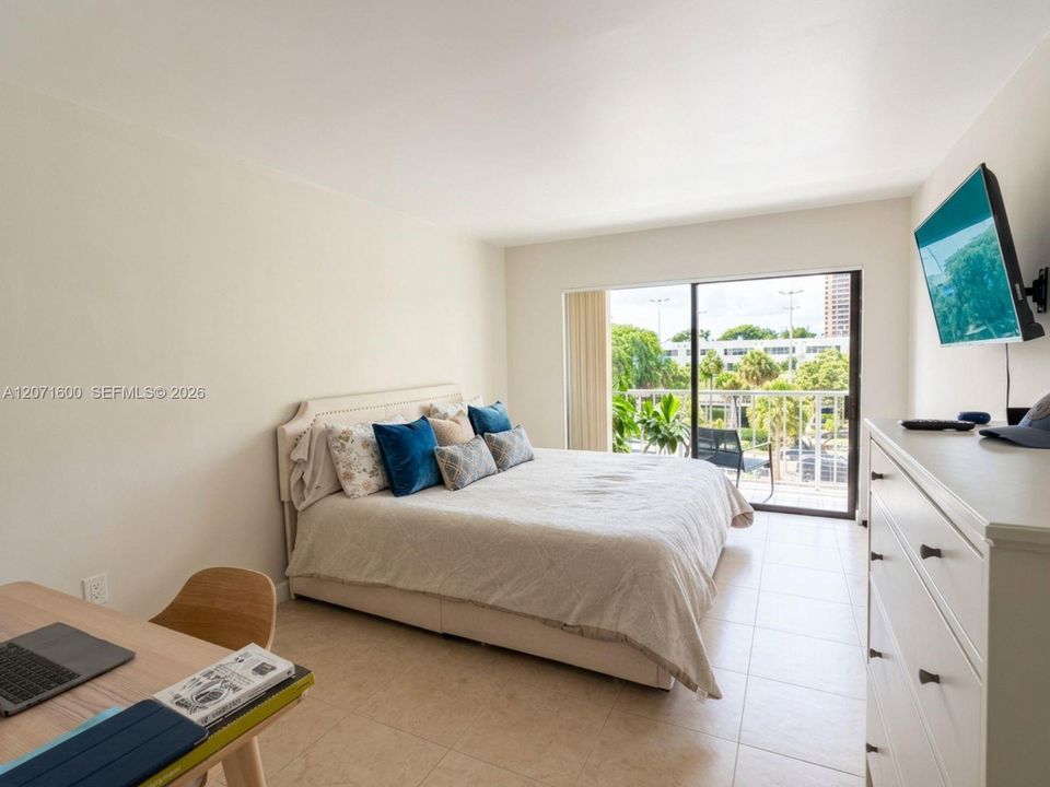 Spacious primary bedroom featuring abundant natural light and direct access to the private balcony.