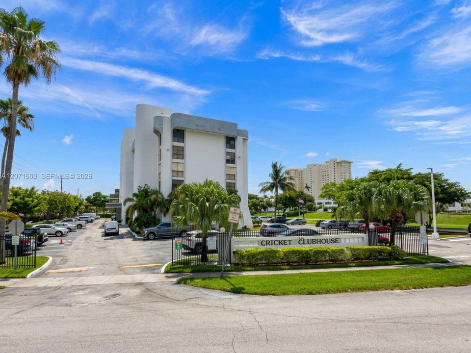Well-maintained residential building featuring a welcoming entrance, lush tropical landscaping, and gated access.