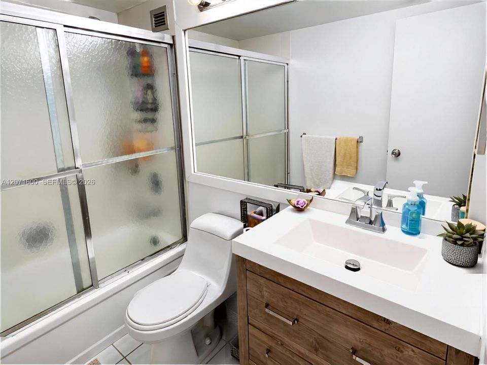 Tastefully updated full bathroom featuring a modern wood vanity, sleek fixtures, and a glass-enclosed shower.